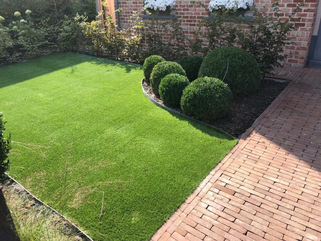 groen kunstgras met rechts klinkerwerken, mooi afgeboord